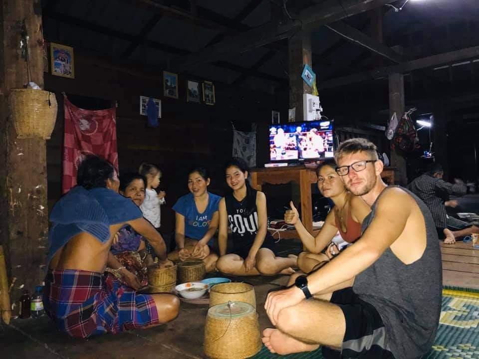 familie sitzt am boden und isst gemeinsam klebreis in laos