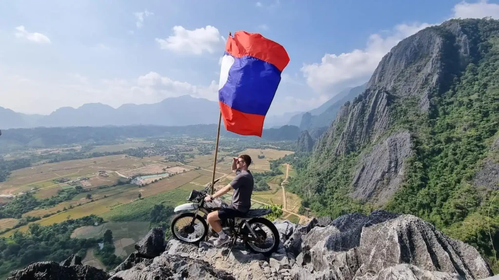 silver cliff aussichtspunkt vang vieng mit laotischer flagge